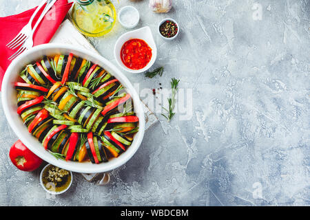 Vegetarische Rohkost Ratatouille aus Auberginen, Zucchini, Tomaten und Paprika Sauce und Tomaten mit Kräutern in keramischen Form vor dem Backen. Ansicht von oben Stockfoto