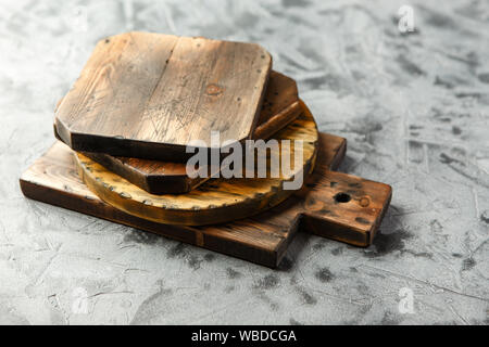 Stapel von verschiedenen hölzerne Schneidbretter auf grauem Hintergrund. Stockfoto