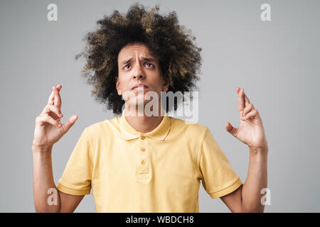 Foto von Ernst kaukasischen Mann mit Afro Frisur runzelte die Stirn und halten die Daumen über grauer Hintergrund Stockfoto