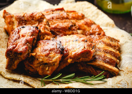 Gegrillte Schweinerippchen auf dünnen Pita in der Platte auf braunem Hintergrund Stockfoto