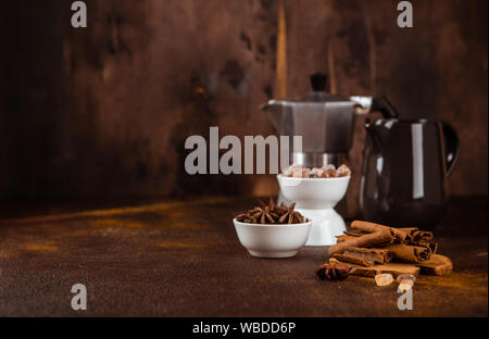 Zimtstangen, Anis*, Karamellzucker, Kaffeekanne und Milchkännchen auf einem dunklen Hintergrund Stockfoto