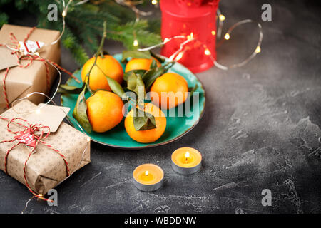 Mandarinen in grüne Platte mit Kerzen und Geschenkboxen Stockfoto