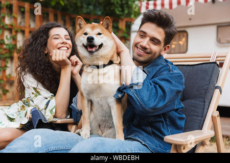 Bild der romantischen lächelndes Paar Mann und Frau in der Nähe von Anhänger mobile home Ihr Hund umarmt. Stockfoto