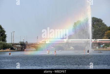 Hamburg, Deutschland. 26 Aug, 2019. Auf Stand-up-Boards, kühlen Sie sich bei Temperaturen über 30 Grad Celsius an der Binnenalster Fontäne auf der Binnenalster, wo Sonnenlicht bricht und die Farben des Regenbogens zeigen. Credit: Bodo Marks/dpa/Alamy leben Nachrichten Stockfoto