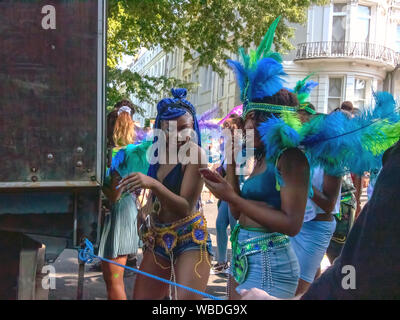 Maskierten hinter einem Lkw während der Feier. Die wichtigsten Ereignisse der Notting Hill Carnival 2019 angelaufen, mit über einer Million revellers schlagen die Straßen von West London, unter den Schwimmern, maskierten, Steel Bands und Sound Systeme. Stockfoto