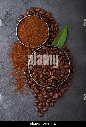 Frische rohe organische Kaffeebohnen mit Pulver und Kaffee trea Blatt auf Schwarz Stockfoto