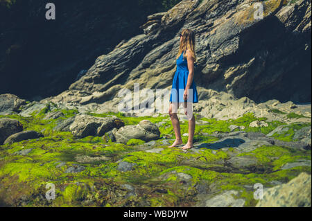 Eine junge Frau steht auf einer felsigen Strand im Sommer Stockfoto