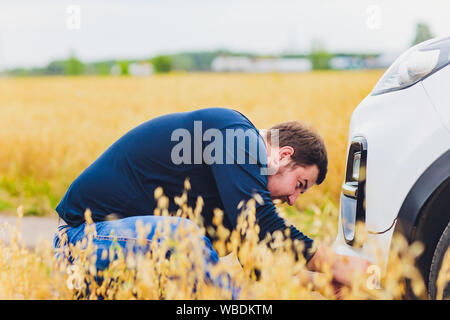 Gestresst und frustriert Fahrer seine Haare ziehen, während auf der Straße neben dem kaputten Auto. Road Trip Probleme und Hilfe Konzepte. Rauch Stockfoto