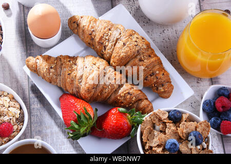 Frühstück serviert mit Kaffee, Orangensaft, Croissants, Eier, Müsli und Obst. Ausgewogene Ernährung. Stockfoto