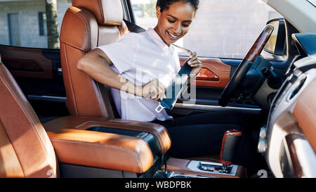 Ormationen lächelnde Frau in ihrem Auto sitzen adjusing Sicherheitsgurt Stockfoto