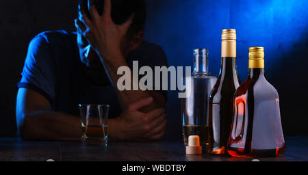 Flaschen mit alkoholischen Getränken und die Abbildung von einem betrunkenen Mann Stockfoto