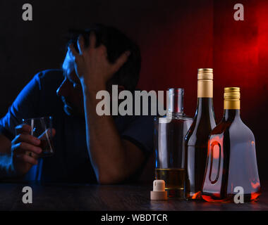 Flaschen mit alkoholischen Getränken und die Abbildung von einem betrunkenen Mann Stockfoto