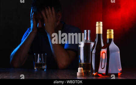 Flaschen mit alkoholischen Getränken und die Abbildung von einem betrunkenen Mann Stockfoto