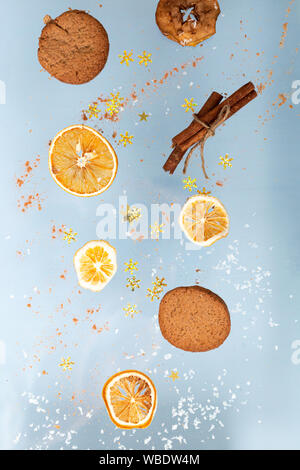 Ingwer cookies mit trockenen Apple und orangen Scheiben und Zimtstange Fliegen auf blauem Hintergrund. Essen Levitation. Weihnachten Konzept Stockfoto