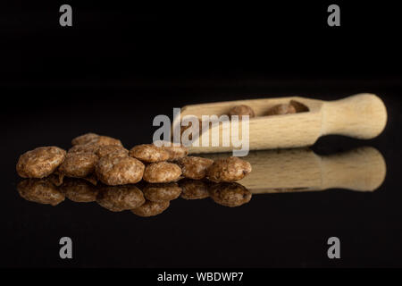 Menge ganze Schokolade Kugel Frühstücksflocken mit Holz- Schaufel auf schwarz Glas isoliert Stockfoto
