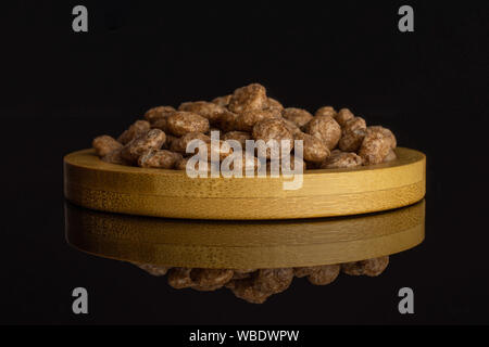 Menge ganze Schokolade Kugel Frühstückszerealien auf Bambus Platte auf schwarzem Glas isoliert Stockfoto