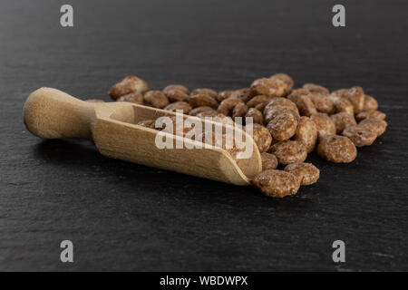 Menge ganze Schokolade Kugel Frühstücksflocken mit Holz- Schaufel auf grauem Stein Stockfoto