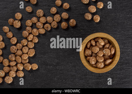 Menge ganze Schokolade Kugel Frühstückszerealien in Houten flatlay am grauen Stein Stockfoto
