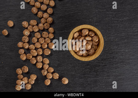 Menge ganze Schokolade Kugel Frühstückszerealien in Houten flatlay am grauen Stein Stockfoto