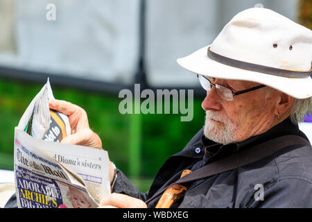 Nahaufnahme von Senior Kaukasier Männlich lesen Die E-Zeitung. Mann trägt weiße Trilby Hut, hat einen weißen Bart, und trägt eine Brille. Stockfoto