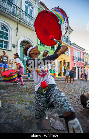 SALVADOR, Brasilien - Februar, 2018: Eine junge brasilianische Mann zeigt seine Stärke in einer Gruppe von Roving trommler als Teil einer Gemeinschaft. Stockfoto
