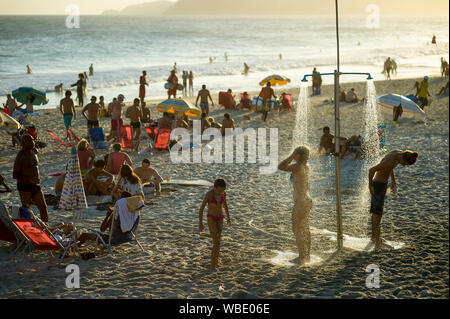 RIO DE JANEIRO - 15. FEBRUAR 2018: Beachgoers abspülen, wie die Sonne auf einen beschäftigten Sommer am Nachmittag am Strand von Ipanema. Stockfoto