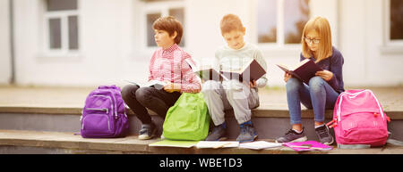 Kinder mit Rucksäcken stehen im Park in der Nähe von Schule Stockfoto