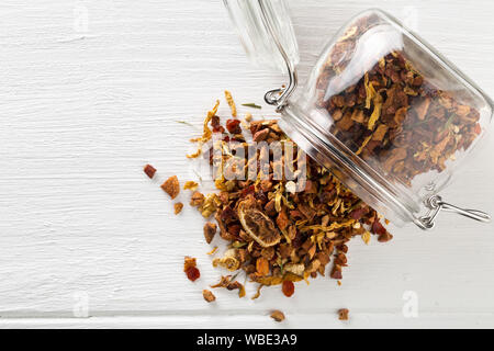 Haufen getrockneter Früchte Tee Infusion mit Orangen und Erdbeeren mit Teeblätter und verschiedene Kräuter im Glas auf weissem Holztisch bac gemischt Stockfoto