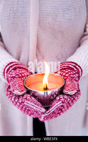 Selektiver Fokus auf Frau gestrickte Handschuhe und Pullover Holding leuchtet eine Kerze im Freien (auch als pitch Taschenlampe oder einen Garten Kerze bekannt), im Freien, in w Stockfoto
