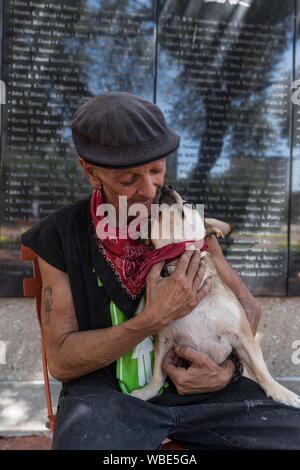 Frank Smith, einen behinderten Weltkriegveteran, verbringt viel seiner Zeit auf den Straßen von Fort Worth, sitzt mit seinem Hund vor der Luftfahrt Wand der Ehre im Allgemeinen Wert Square in der Innenstadt von Fort Worth, Texas Stockfoto