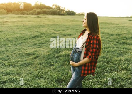 Weiß brunette schwangere Frau in Jeans Overalls Stockfoto