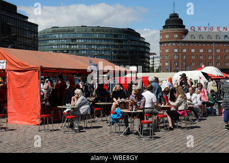 Leute genießen Kaffee an Hakaniemi Marktplatz Cafe mit erkennbaren Ympyrätalo und Arena Gebäude im Hintergrund in Helsinki, Finnland Stockfoto