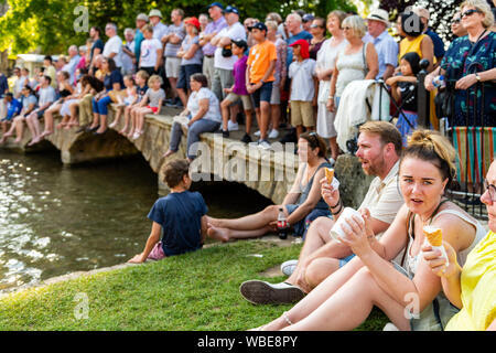 Menschenmassen säumen die Brücke über den Fluss Windrush in Bourton-on-the-Water, Cotswolds, Großbritannien. Geschäftige August Feiertag Montag. Die Leute packten zusammen. Stockfoto