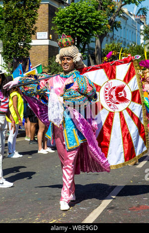 26. August 2019 - Mann, gekleidet in einen Zeitraum Kostüm mit Pulver Perücke, Krone und Flagge in Notting Hill Karneval an einem heißen Feiertag Montag, London, UK Stockfoto