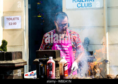 26. August 2019 - Mann grillen Fleisch bei einem behelfsmäßigen Guerilla Jerk Chicken Garküche, Notting Hill Carnival an einem heißen Feiertag Montag, London, UK Stockfoto