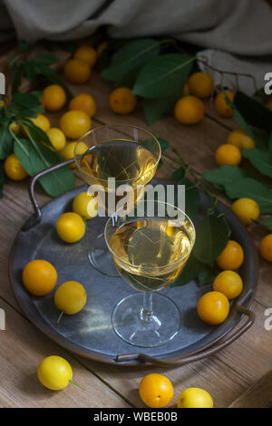Cherry Plum Likör in kleinen Gläsern und Cherry Plum auf einer hölzernen Hintergrund. Im rustikalen Stil. Stockfoto