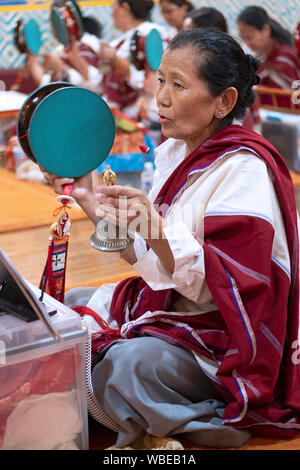 Ein frommer Nepalesischen Buddhistischen betende Frau im Tempel beim Klingeln einer Glocke & Drehen eines Damaru drum. In Elmhurst, Queens, New York City. Stockfoto