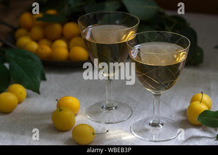 Cherry Plum Likör in kleinen Gläsern und Cherry Plum auf einer hölzernen Hintergrund. Im rustikalen Stil. Stockfoto