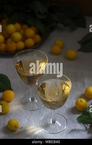 Cherry Plum Likör in kleinen Gläsern und Cherry Plum auf einer hölzernen Hintergrund. Im rustikalen Stil. Stockfoto