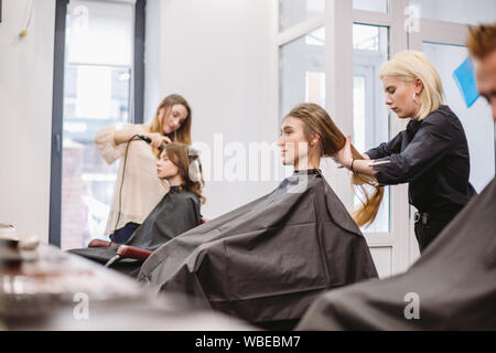 Schöne Frau kämmen nasse Haar. stylist Bürsten Frau Haar im Salon. Friseur mit Kunden. Professionelle young Friseur Arbeiten mit Kamm Stockfoto