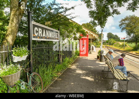 CRANMORE, ENGLAND - Juli 2019: Menschen sitzen auf einer Bank warten auf einen Zug bei Cranmore Station auf der East Somerset Railway. Stockfoto