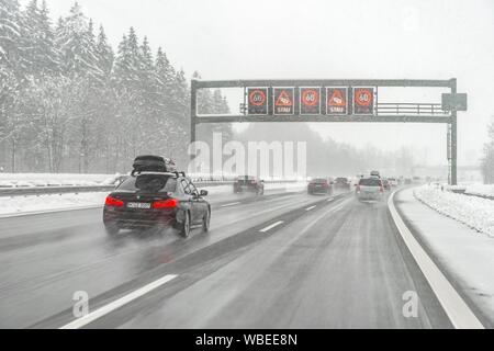 Staugefahr und Geschwindigkeitsbegrenzungen, schlechtes Wetter, Auto Verkehr während starker Schneefall und Regen auf der Autobahn A8, in der Nähe von München, Bayern, Deutschland Stockfoto