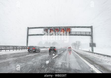 Staugefahr und Geschwindigkeitsbegrenzungen, schlechtes Wetter, Auto Verkehr während starker Schneefall und Regen auf der Autobahn A8, in der Nähe von München, Bayern, Deutschland Stockfoto