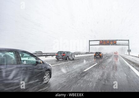 Staugefahr und Geschwindigkeitsbegrenzungen, schlechtes Wetter, Auto Verkehr während starker Schneefall und Regen auf der Autobahn A8, in der Nähe von München, Bayern, Deutschland Stockfoto