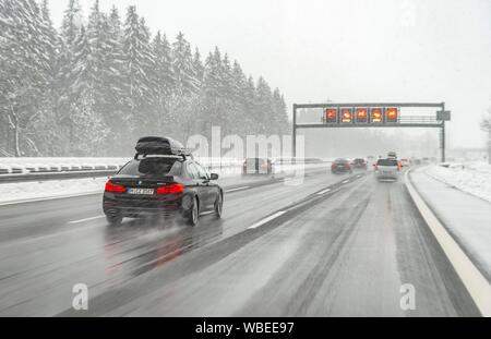 Staugefahr und Geschwindigkeitsbegrenzungen, schlechtes Wetter, Auto Verkehr während starker Schneefall und Regen auf der Autobahn A8, in der Nähe von München, Bayern, Deutschland Stockfoto