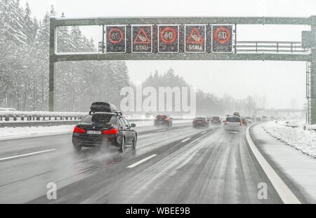 Staugefahr und Geschwindigkeitsbegrenzungen, schlechtes Wetter, Auto Verkehr während starker Schneefall und Regen auf der Autobahn A8, in der Nähe von München, Bayern, Deutschland Stockfoto