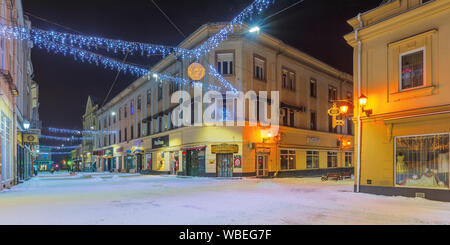 Uschhorod, Ukraine - 06 Jan, 2019: Winter Nacht in der Stadt. wundervolle Weihnachten illumitation. Leere Korzo Straße im Schnee bedeckt. Panoramaaussicht Stockfoto