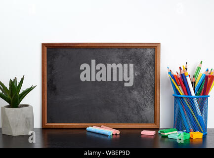 Leere Schwarze Kreide, multi-Bleistifte in einem blauen Metall stehen auf einer schwarzen Tabelle farbig, Konzept Zurück zur Schule Stockfoto