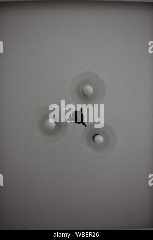 Bild von unten mit einem Kronleuchter, 3 Glühbirnen gegen eine weiße Decke Stockfoto