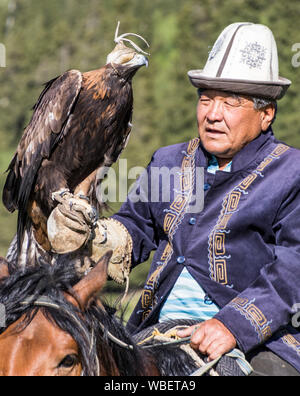 Issyk Kul, Kirgisistan - Mai 28, 2017 - Adler Jäger hält sich die Adler auf dem Arm vor der Jagd Stockfoto